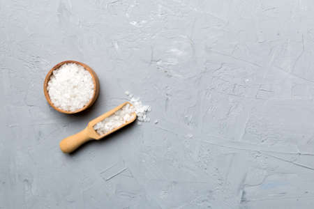 A wooden bowl of salt crystals on a wooden background. Salt in rustic bowls, top view with copy space.の写真素材