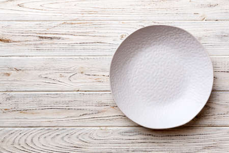 Top view of empty light plate on wooden background. Empty space for your design.