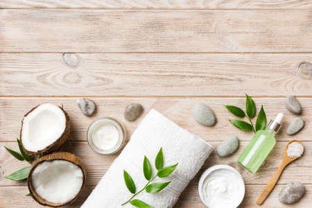 Coconut with jars of coconut oil and cosmetic cream on wooden background. top view. Free space for your text. Natural spa coconut cosmetics and organic treatment concept Coconut Spa composition.の写真素材