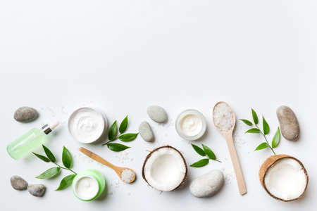 Coconut with jars of coconut oil and cosmetic cream on colored background. top view. Free space for your text. Natural spa coconut cosmetics and organic treatment concept Coconut Spa composition.の写真素材