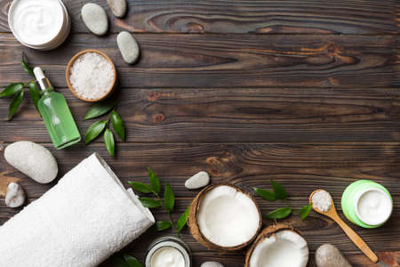 Coconut with jars of coconut oil and cosmetic cream on wooden background. top view. Free space for your text. Natural spa coconut cosmetics and organic treatment concept Coconut Spa composition.の写真素材
