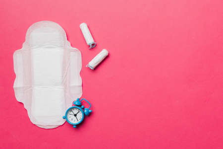 Ringing alarm clock with sanitary female tampons and menstrual sanitary pads. Medical concept of woman critical days and menstruation. Female daily hygiene. copyspace.の写真素材