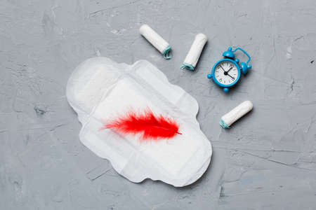 Ringing alarm clock with sanitary female tampons and menstrual sanitary pads. Medical concept of woman critical days and menstruation. Female daily hygiene. copyspace.の写真素材