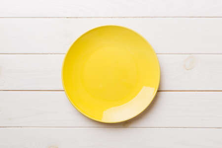 Top view of empty yellow plate on wooden background. Empty space for your design.の写真素材