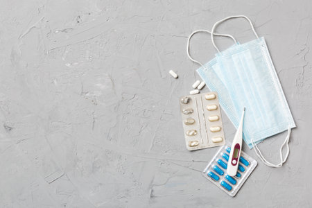 Protective face masks or surgical masks, medicine pills and thermometer on table background. coronavirus disease. Corona virus concept. Space for text.の写真素材