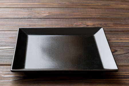 Perspective view of empty square plate on wooden background. Empty space for your design.の写真素材