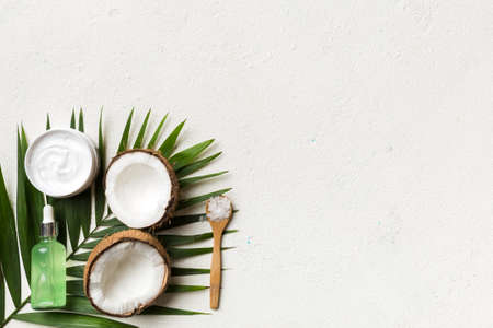 Coconut with jars of coconut oil and cosmetic cream on colored background. top view. Free space for your text. Natural spa coconut cosmetics and organic treatment concept Coconut Spa composition.の写真素材
