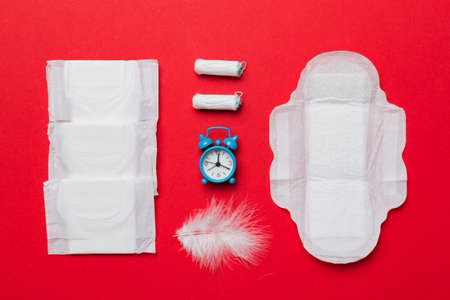 Ringing alarm clock with sanitary female tampons and menstrual sanitary pads. Medical concept of woman critical days and menstruation. Female daily hygiene. copyspace.の写真素材
