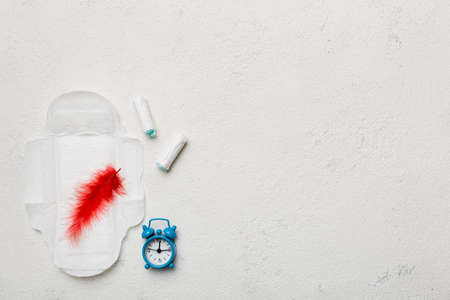 Ringing alarm clock with sanitary female tampons and menstrual sanitary pads. Medical concept of woman critical days and menstruation. Female daily hygiene. copyspace.の写真素材