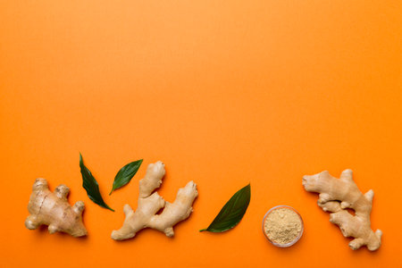 Finely dry Ginger powder in bowl with green leaves isolated on colored background. top view flat lay.の写真素材