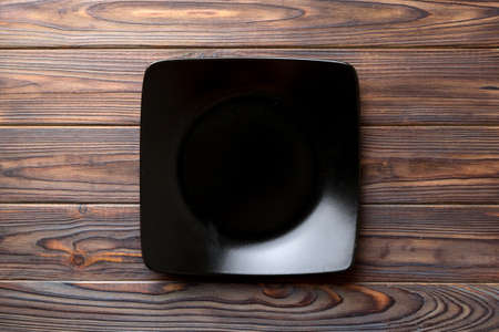 Top view of empty square plate on wooden background. Empty space for your design.