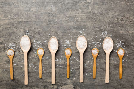 salt on wooden spoon on wood background. Spoons with different salt.の写真素材