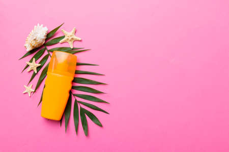 Sunscreen spray bottle. Bottle with sun protection cream and sea shells with tropical green leaf on...