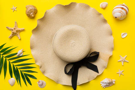 Summer holidays. Summer concept with straw hat and tropical leaf. Flat lay, top view, copy space.