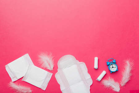 Ringing alarm clock with sanitary female tampons and menstrual sanitary pads. Medical concept of woman critical days and menstruation. Female daily hygiene. copyspace.の写真素材