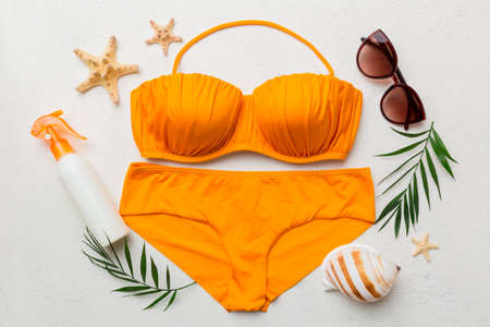Woman swimwear and beach accessories flat lay top view on colored background Summer travel concept. bikini swimsuit, straw hat and seasheels. Copy space top view.の写真素材