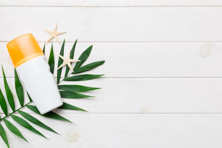 Sunscreen spray bottle. Bottle with sun protection cream and sea shells with tropical green leaf on...