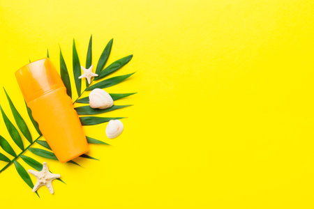 Sunscreen spray bottle. Bottle with sun protection cream and sea shells with tropical green leaf on...