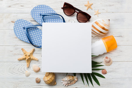 Summer time concept with blank greeting card and blank white paper on colored background. Seashells from ocean shore in the shape of frame separated with space for text top view.の写真素材