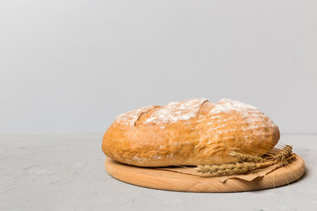 Freshly baked bread on cutting board against white wooden background. perspective view bread with...