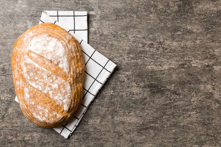 Freshly baked delicious french bread with napkin on rustic table top view. Healthy white bread loaf.