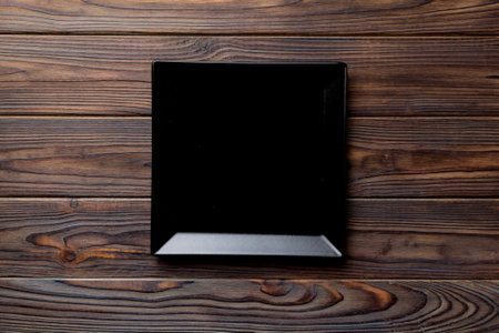 Top view of empty square plate on wooden background. Empty space for your design.の写真素材
