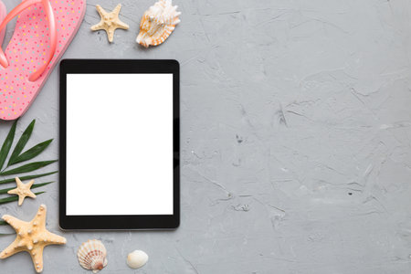 Flat lay composition with tablet and beach accessories on colored background. Tablet computer with blank screen mock up with copy space.の写真素材