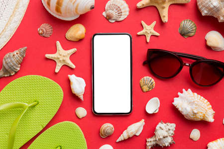 Flat lay composition with Phone and beach accessories on colored background. Smartphone with blank screen mock up with copy space.の写真素材