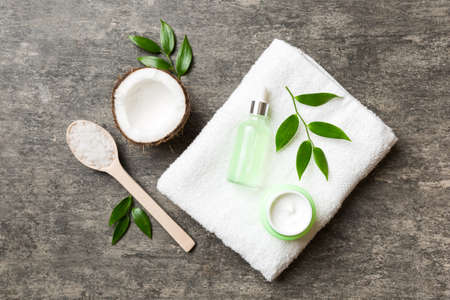 Coconut with jars of coconut oil and cosmetic cream on colored background. top view. Free space for your text. Natural spa coconut cosmetics and organic treatment concept Coconut Spa composition.の写真素材