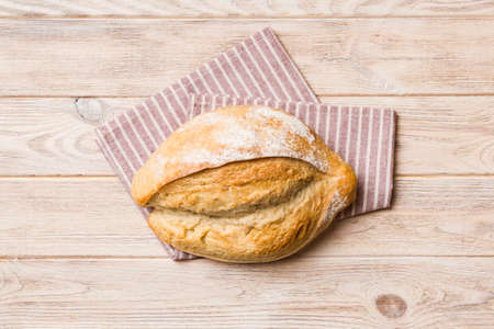 Freshly baked delicious french bread with napkin on rustic table top view. Healthy white bread loaf.