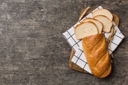 Freshly baked bread slices on cutting board against white wooden background. top view Sliced bread.の写真素材