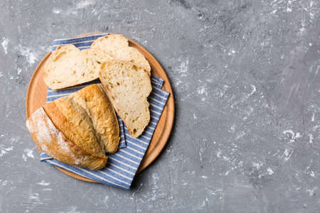 Freshly baked bread slices on cutting board against white wooden background. top view Sliced bread.