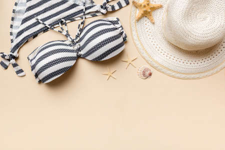 Woman swimwear and beach accessories flat lay top view on colored background Summer travel concept. bikini swimsuit, straw hat and seasheels. Copy space top view.の写真素材