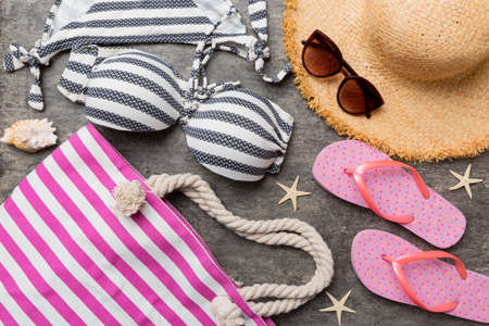 Woman swimwear and beach accessories flat lay top view on colored background Summer travel concept. bikini swimsuit, straw hat and seasheels. Copy space top view.の写真素材
