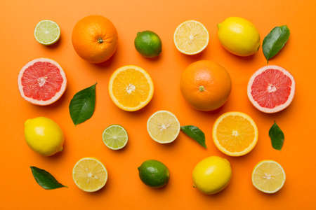 Flat lay of citrus fruits like lime, orange and lemon with lemon tree leaves on light colored...