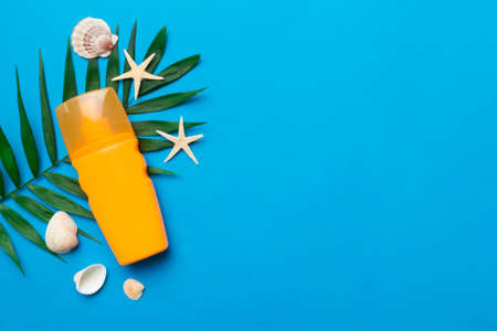 Sunscreen spray bottle. Bottle with sun protection cream and sea shells with tropical green leaf on...