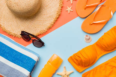 Woman swimwear and beach accessories flat lay top view on colored background Summer travel concept. bikini swimsuit, straw hat and seasheels. Copy space top view.の写真素材