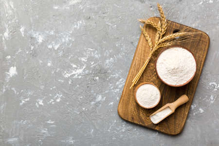 Flat lay of Wheat flour in wooden bowl with wheat spikelets on colored background. world wheat crisis.の写真素材