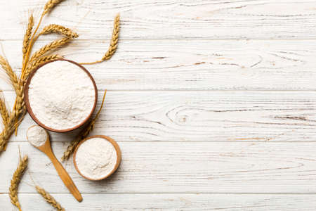 Flat lay of Wheat flour in wooden bowl with wheat spikelets on colored background. world wheat crisis.の写真素材
