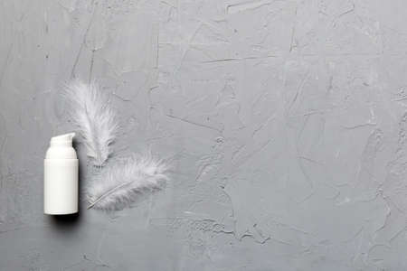 Set of skin care serums on pink pastel background with ostrich feathers. Spa cosmetic product, cream jar, branding mock up, top view with copy space.の写真素材