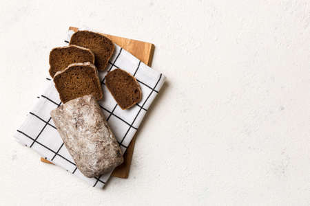 Freshly baked bread slices on cutting board against white wooden background. top view Sliced bread.