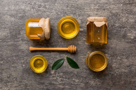 Honey jar with wooden honey dipper on white background top view with copy space. Delicious honey bottle.の写真素材