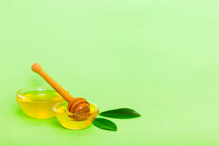 Honey in jar with leaves and honey dipper on colored background top view with copy text.の写真素材