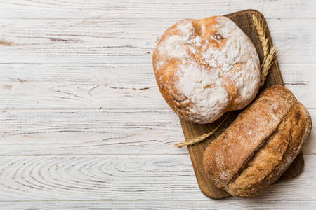 Freshly baked bread on cutting board against white wooden background. top view bread with copy space.の写真素材