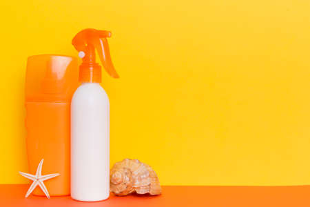 beach accessories. Moisturizer sunscreen suntan lotion bottle for UVB skincare protection in summer with seashells on colored background. Mock up with copyspace.の写真素材