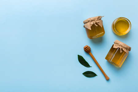 Honey jar with wooden honey dipper on white background top view with copy space. Delicious honey...