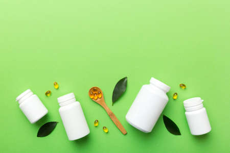 Omega-3 capsules lie in white bottle on a table with green leaves background. fish oil tablets. Biologically active additives. omega 6, omega 9, vitamin A, E, D, vitamin D3 top view with copy space.の写真素材