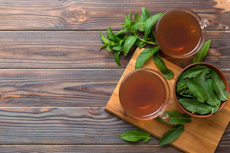 Cup of mint tea on table background. Green tea with fresh mint top view with copy space.