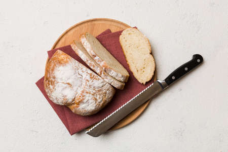 Freshly baked bread cut with knife on a wooden board. top view Sliced bread and knife.