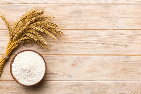 Flat lay of Wheat flour in wooden bowl with wheat spikelets on colored background. world wheat crisis.の写真素材